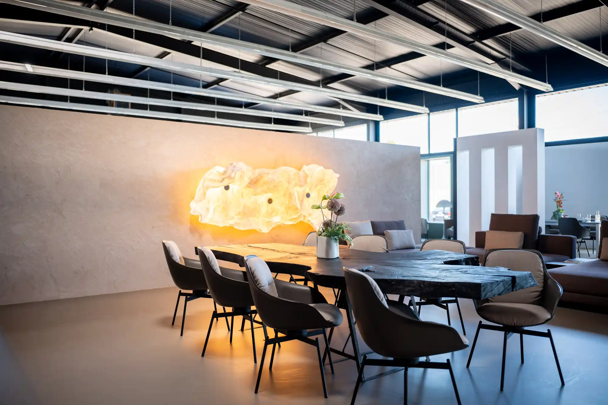 Langer Esstisch vor der beleuchteten Alabasterwand im Showroom