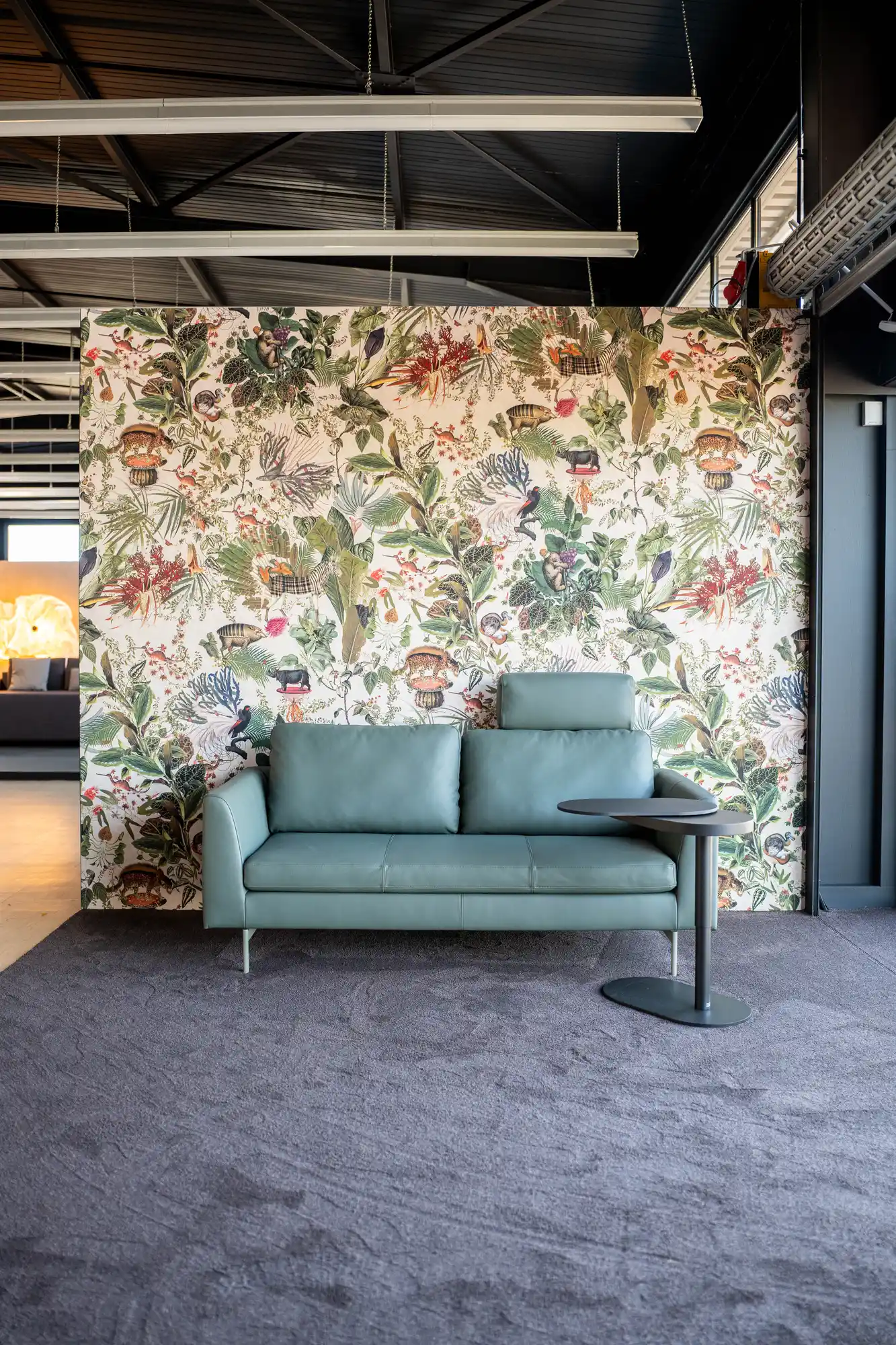 Sofa vor floraler Tapete im Wohnbereich der Ausstellung